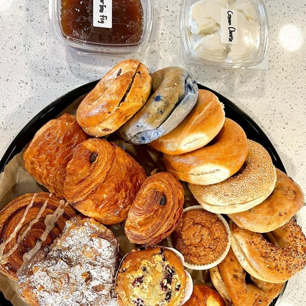 A platter of bagels, croissants, muffins, and pastries, with cream cheese and fig jam.