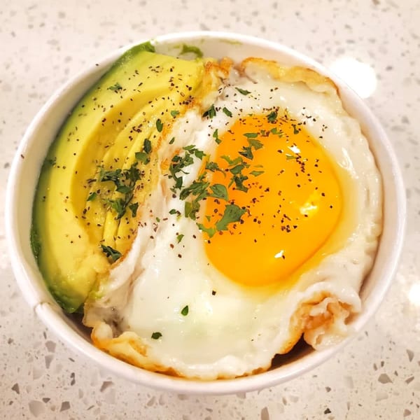 A Sumatra Café breakfast bowl with sliced avocado, a fried egg, and seasonings.